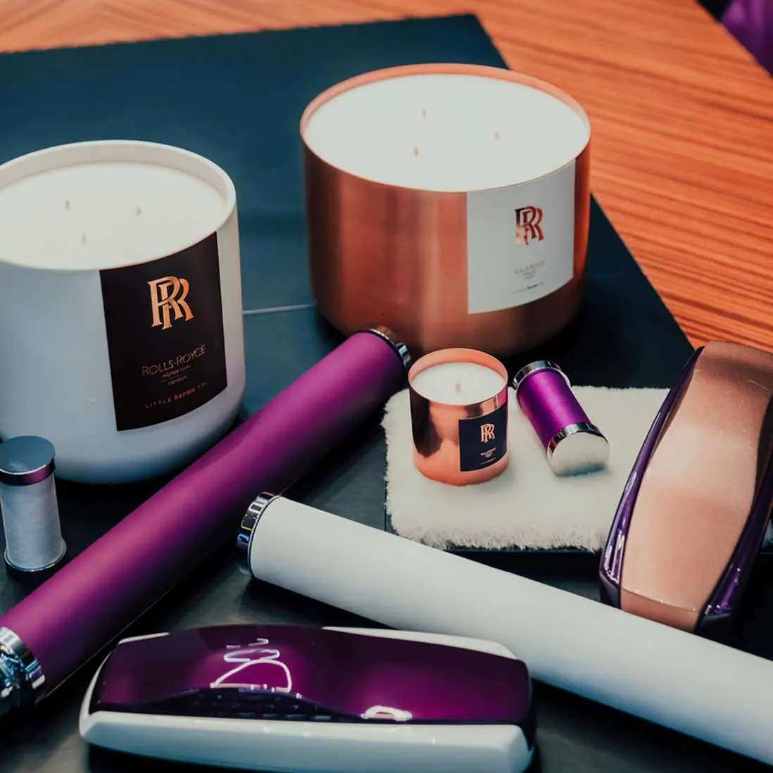 A group of bespoke scented candles in white and copper, styled with branded gifts