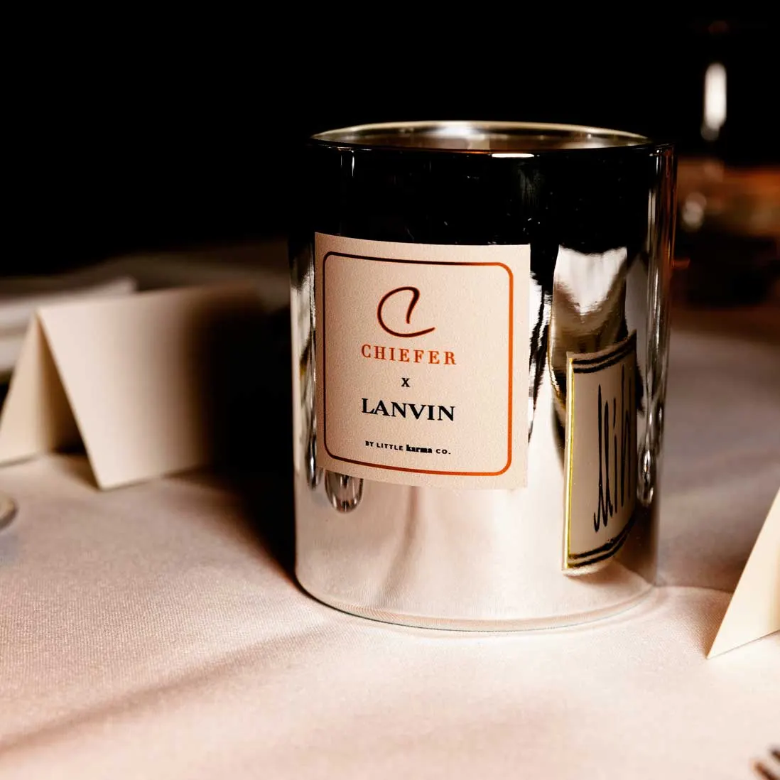 A bespoke scented candle in a mirrored vessel on a dressed table
