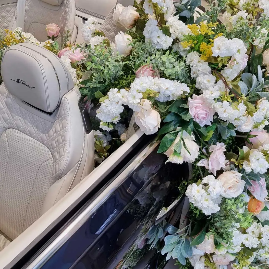 Fresh blooms spilling into the cream leather interior of an open car