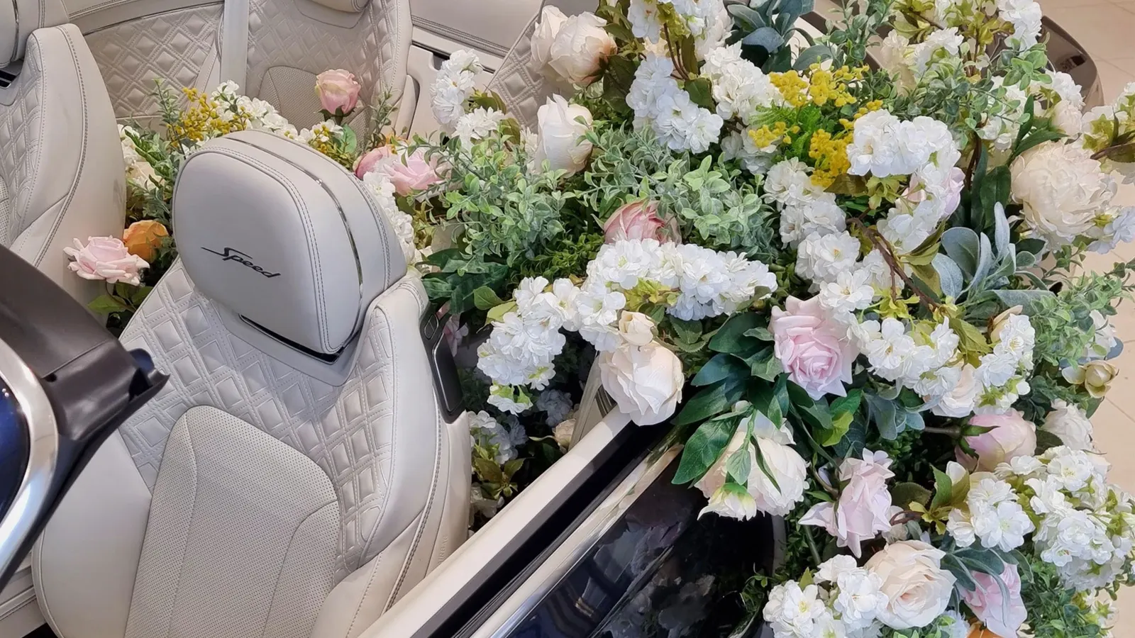 Fresh blooms cascading into the cream leather interior of an open car in a showroom window