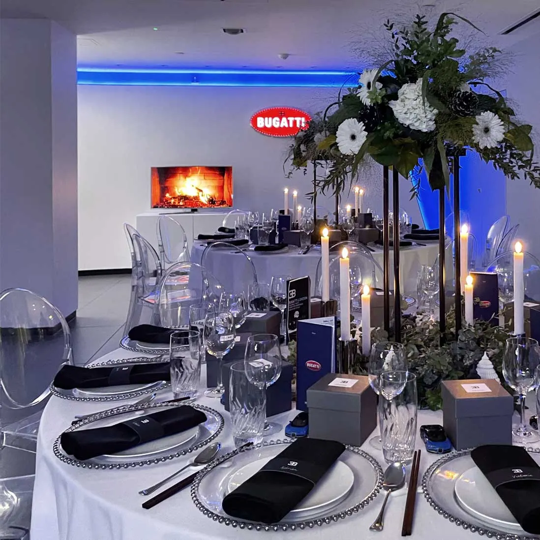 A long table laid with tall white floral centrepieces and candles in a showroom