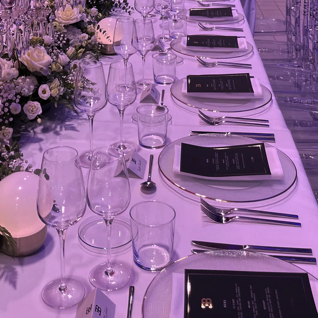 A place setting with menu card, glassware and a floral centrepiece
