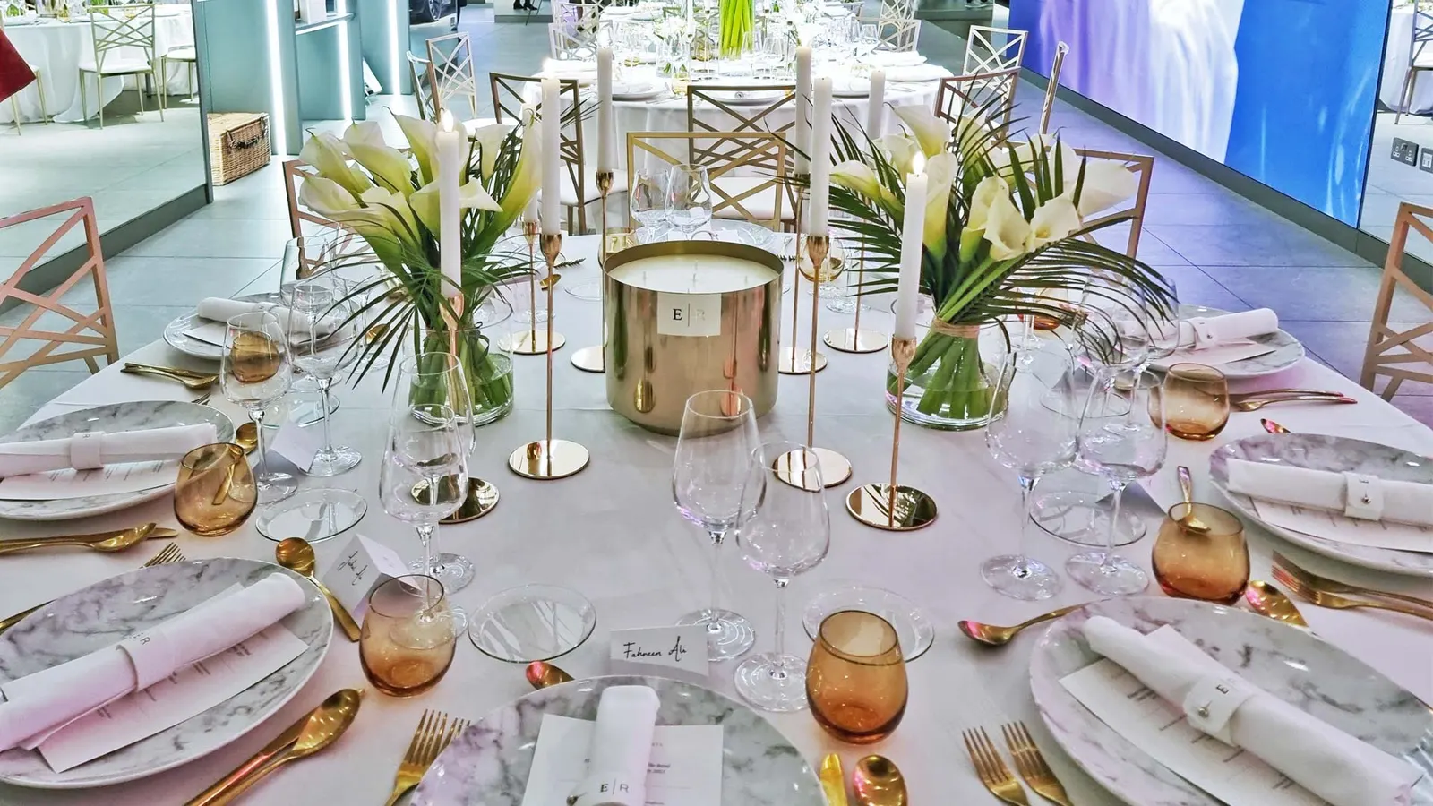 A banqueting table laid with white florals, candles and gold cutlery