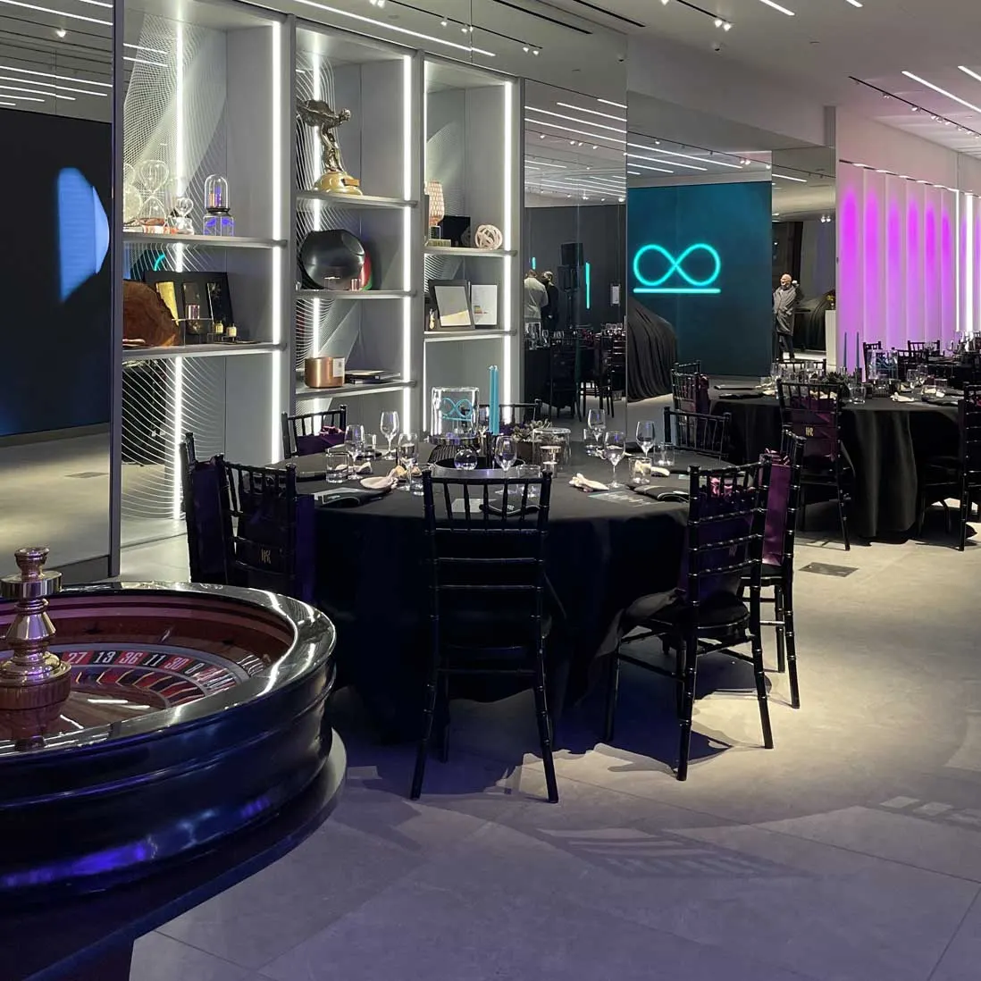 Round tables and chairs set in a showroom beneath a neon light sculpture