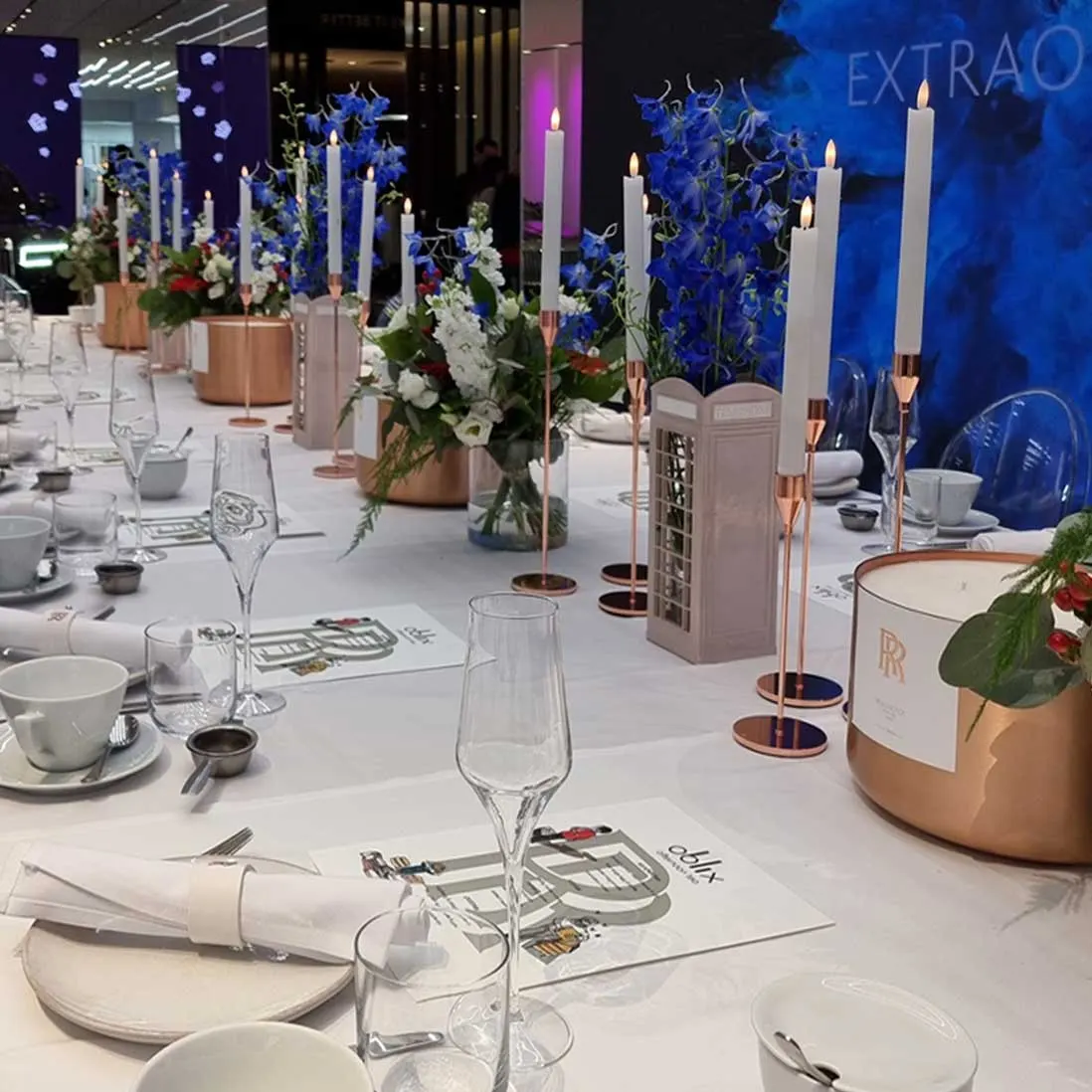 A long table dressed with blue and white florals, copper vessels and tapered candles