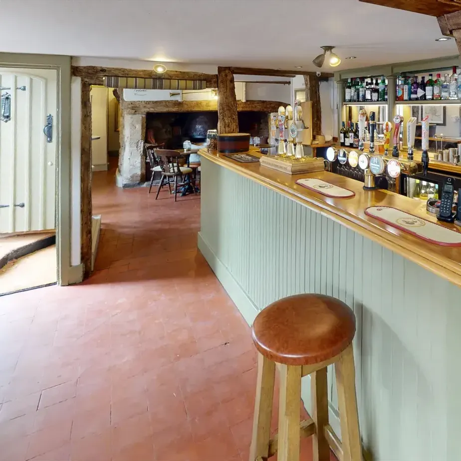 The bar counter in pale green panelling, with a plank door and a tiled floor beside it