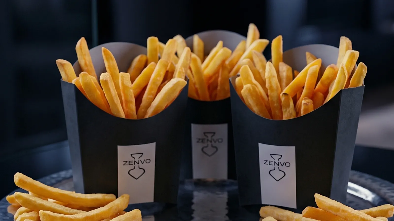 Three branded takeaway cartons of fries head-on, the printed label on each one